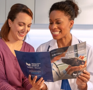 A vet shows her client a pamphlet about the Healthy Habits website